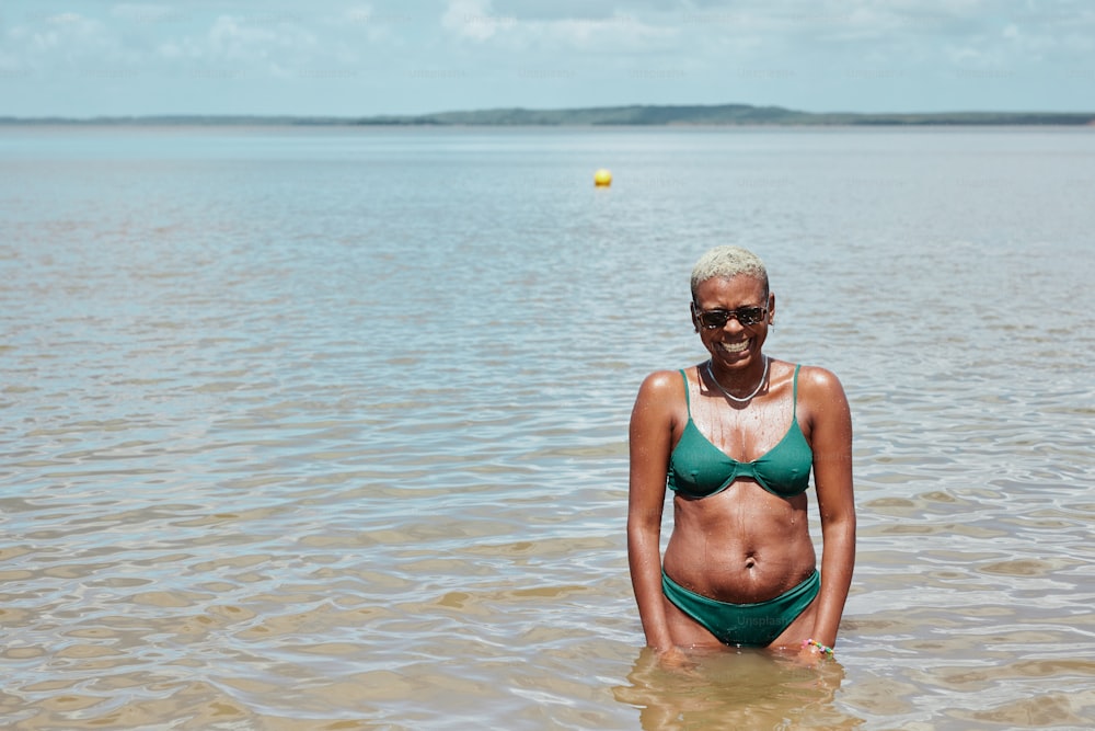 Una mujer en bikini verde parada en el agua
