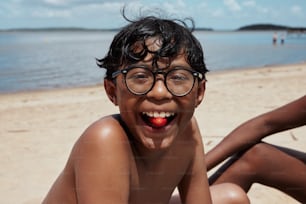 a young boy wearing glasses on the beach