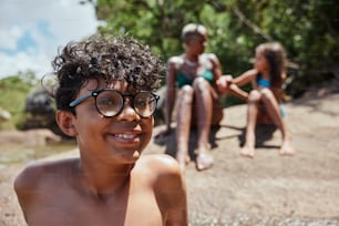 um menino que usa óculos sentado em uma praia