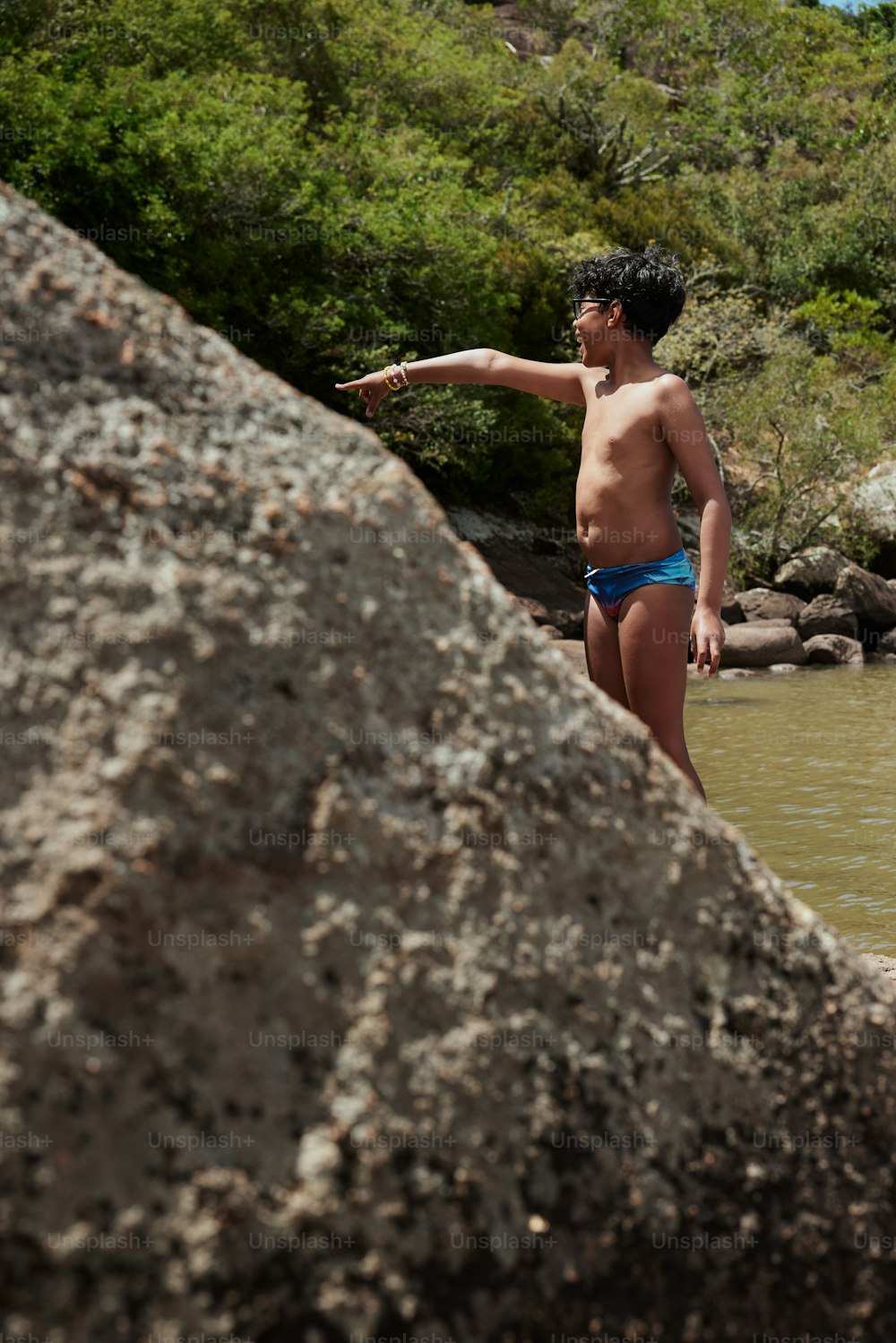 Un hombre en traje de baño parado junto a un cuerpo de agua