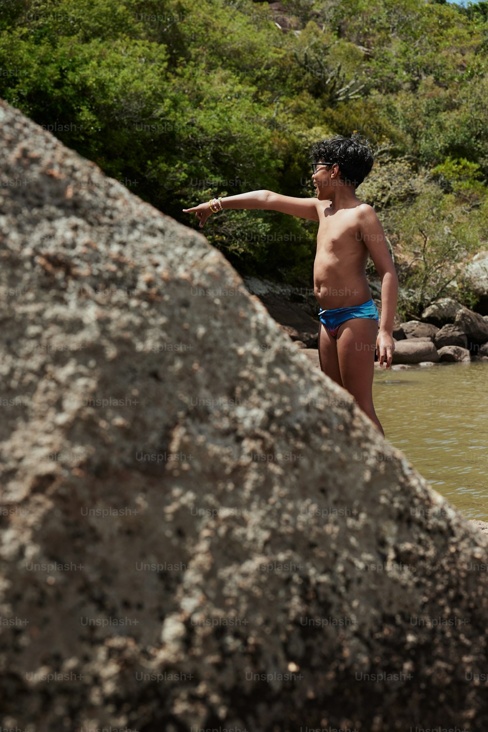 a man in a bathing suit standing next to a body of water