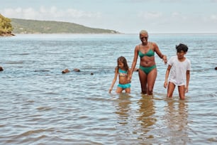 a woman and two children are standing in the water