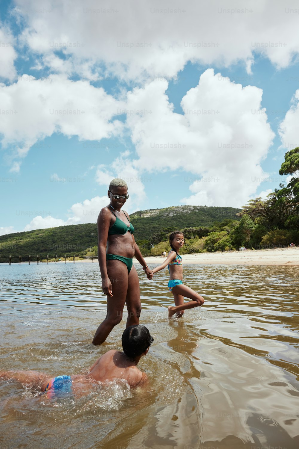 Una mujer en bikini de pie junto a un niño en un cuerpo de agua