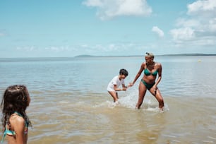 a woman in a bikini and two children playing in the water