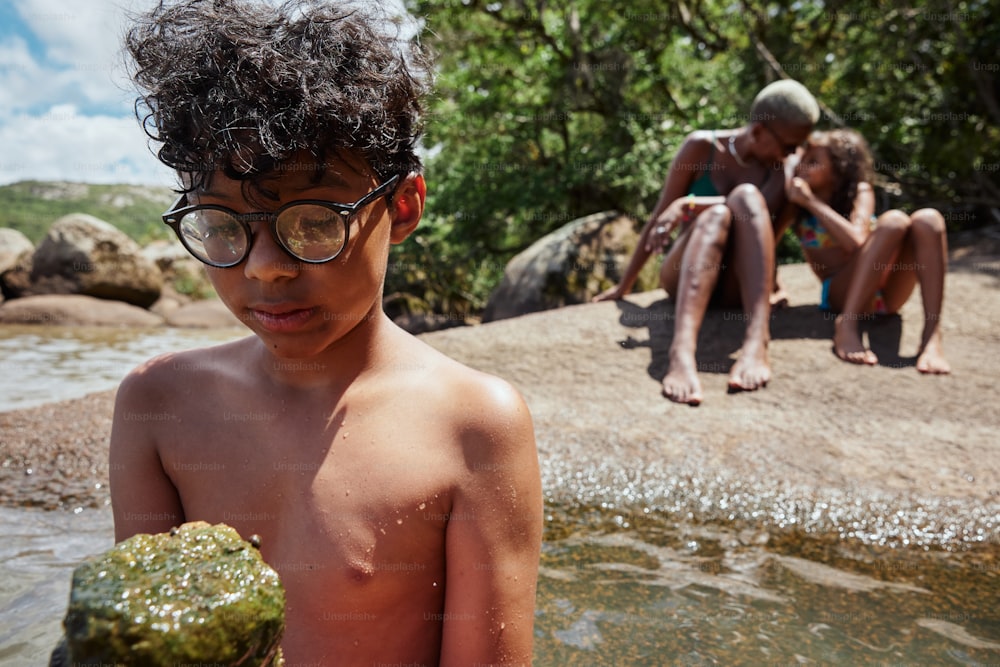 a young boy with glasses standing next to a body of water