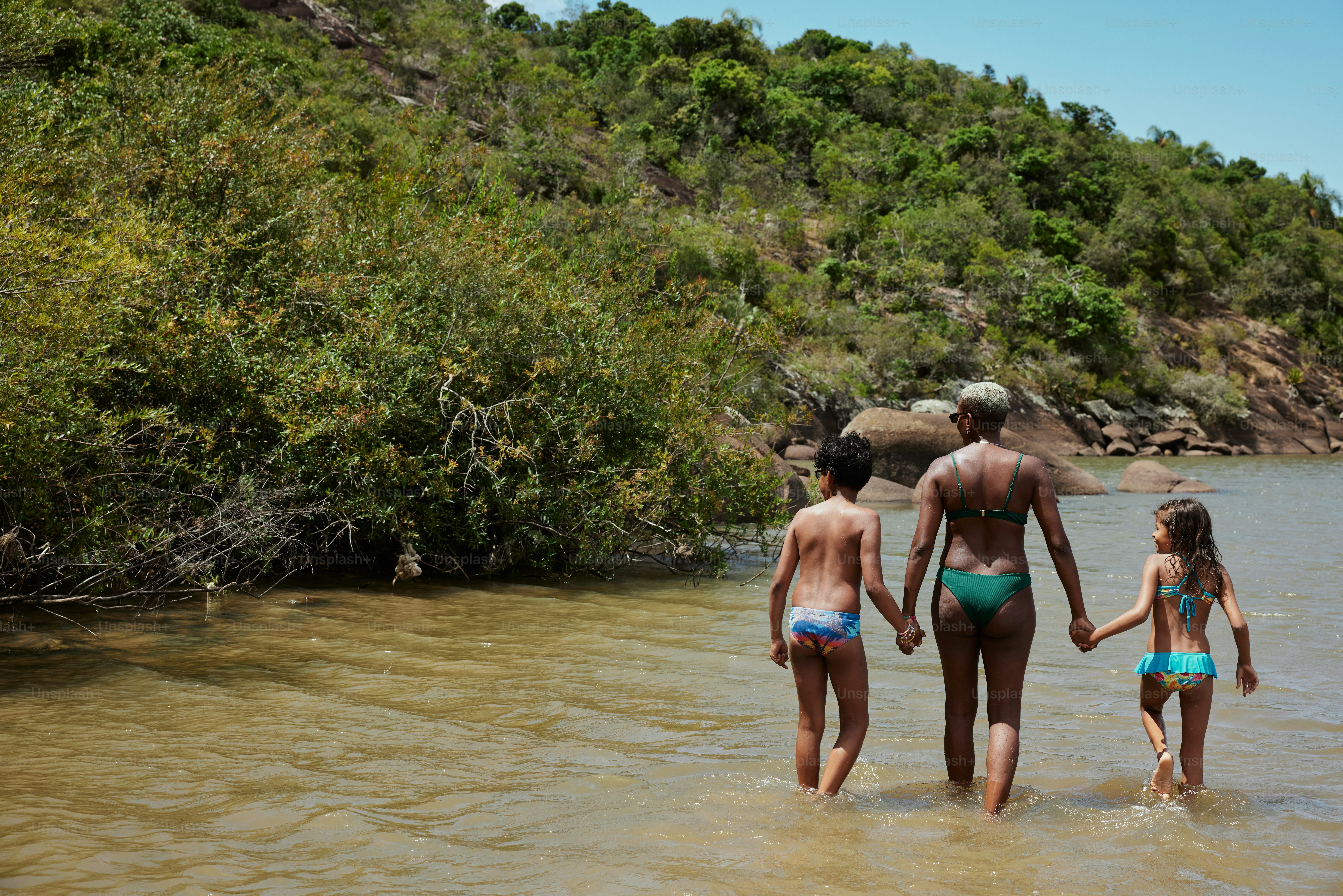 a man and two little girls are walking in the water