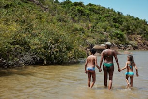 Un homme et deux petites filles marchent dans l’eau