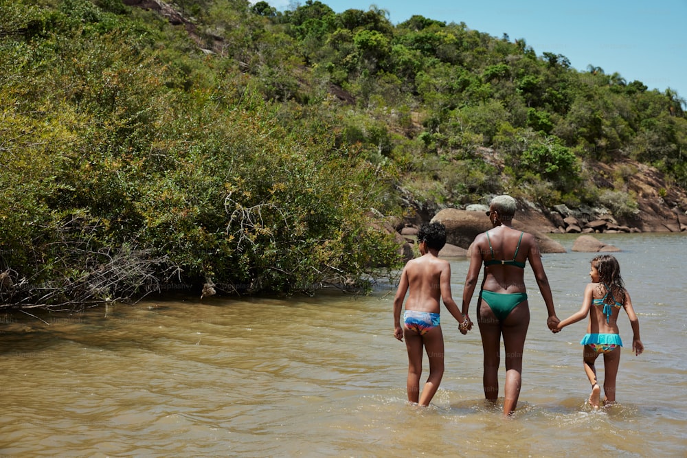 a man and two little girls are walking in the water