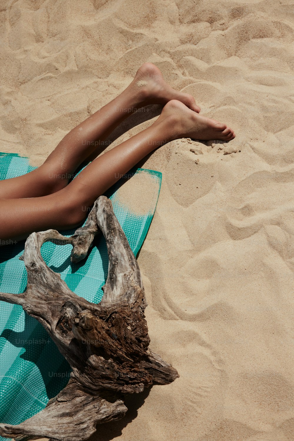 Una donna che si trova sopra un asciugamano blu in cima a una spiaggia sabbiosa