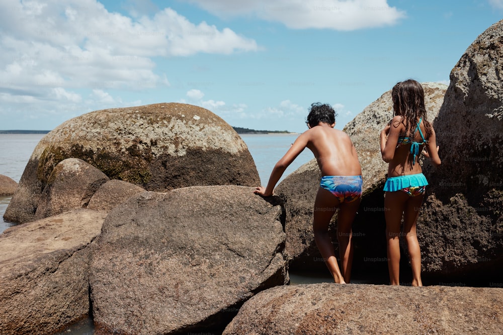 Un par de niños parados encima de grandes rocas