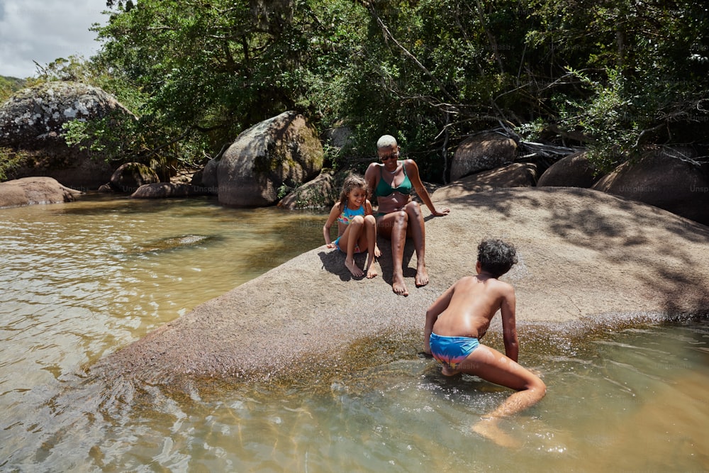 a group of people sitting on a rock in the water