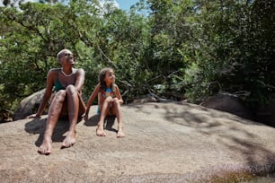 a man and a little girl sitting on a rock