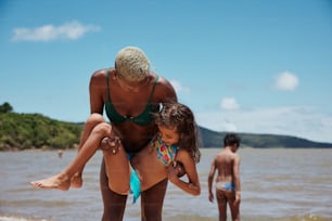 a woman holding a little girl on the beach