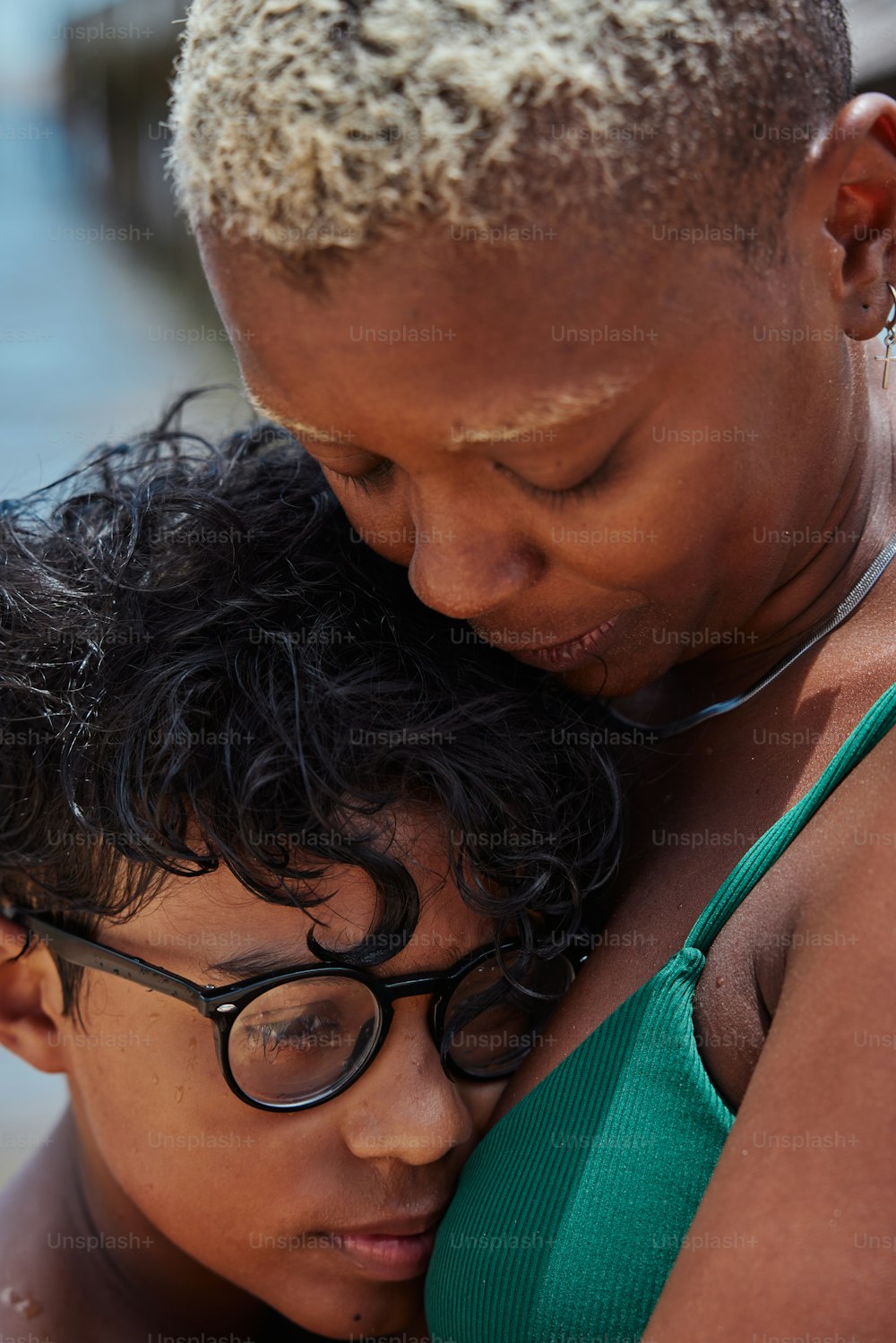 a woman in a green tank top hugging a young boy