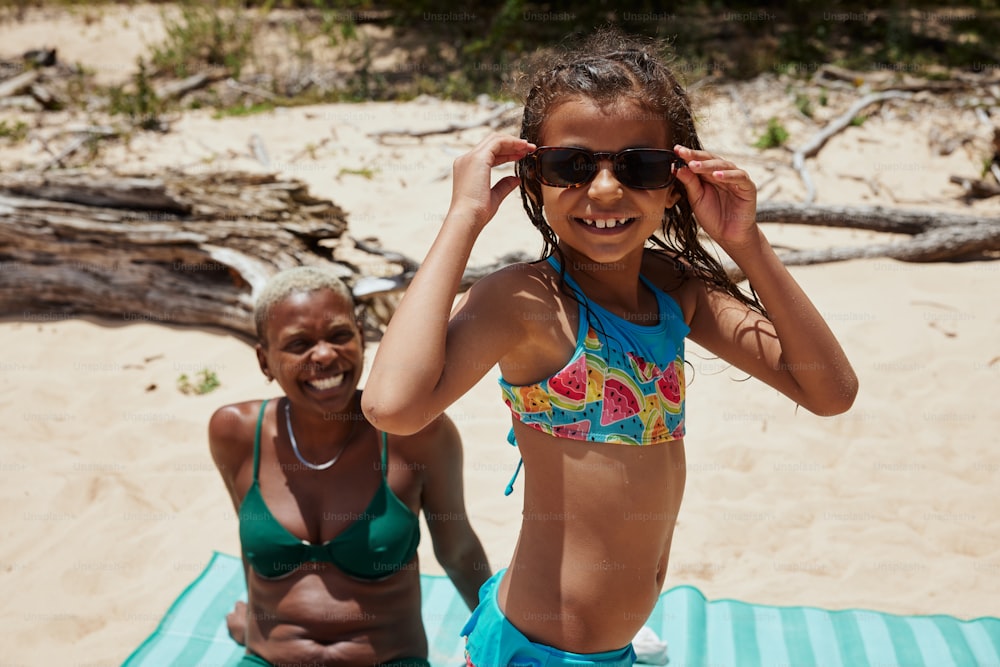 a woman in a bikini standing next to another woman on a beach