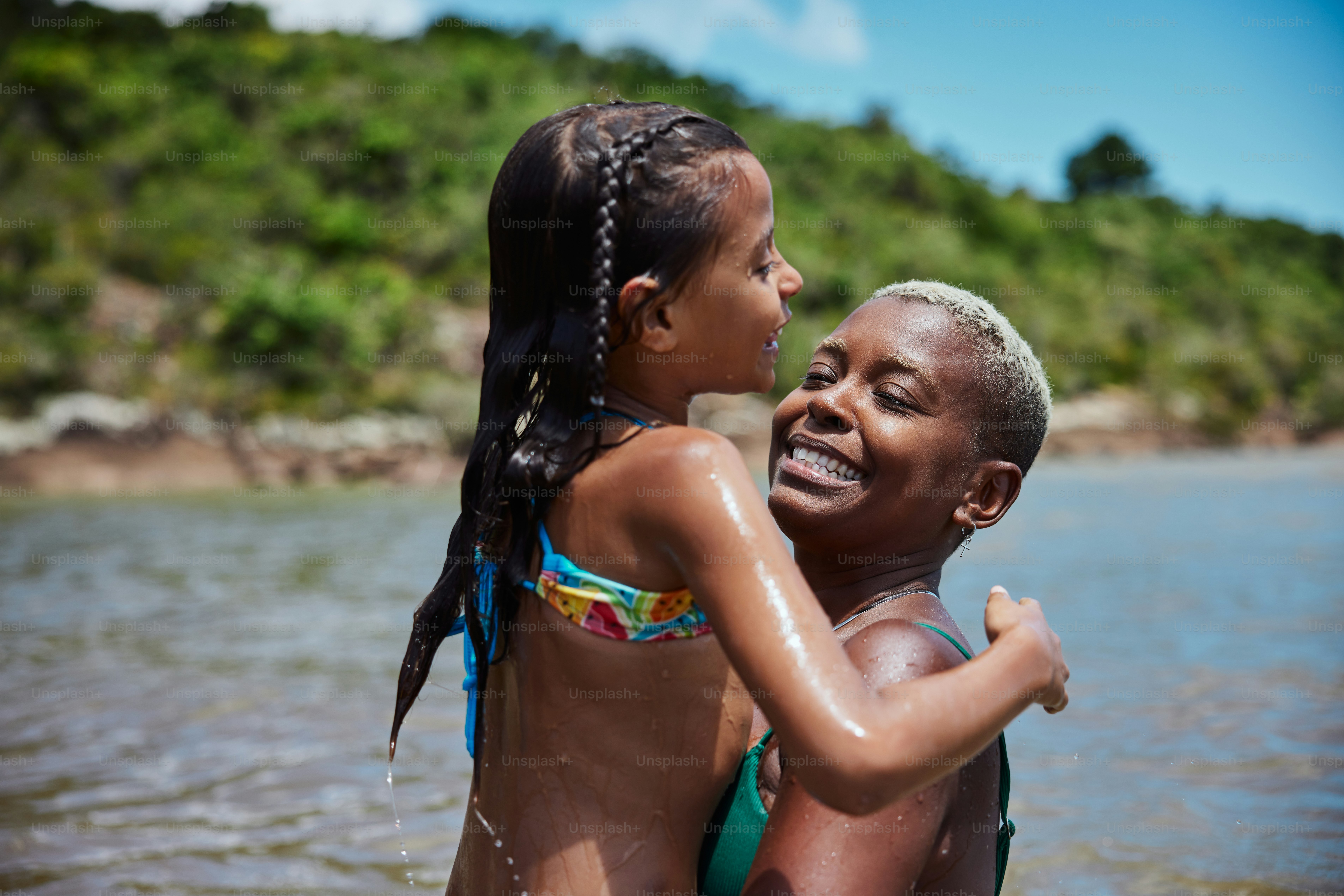 a girl in a bikini hugging another girl in the water