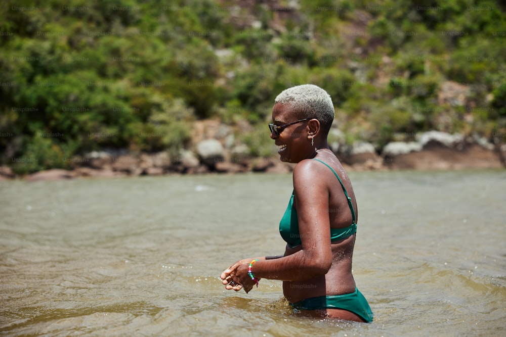 Eine Frau im grünen Badeanzug watet in einem Fluss