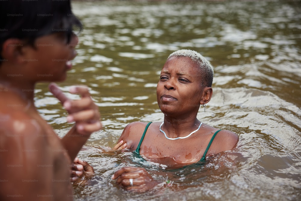 a woman in a body of water talking to another woman