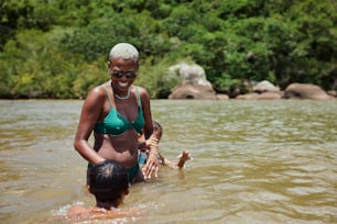 a woman in a green bikini standing next to a child in a river
