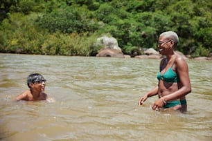 a woman in a bikini standing next to a man in a river