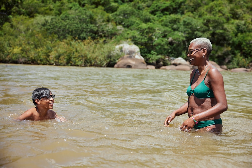 Eine Frau im Bikini steht neben einem Mann in einem Fluss