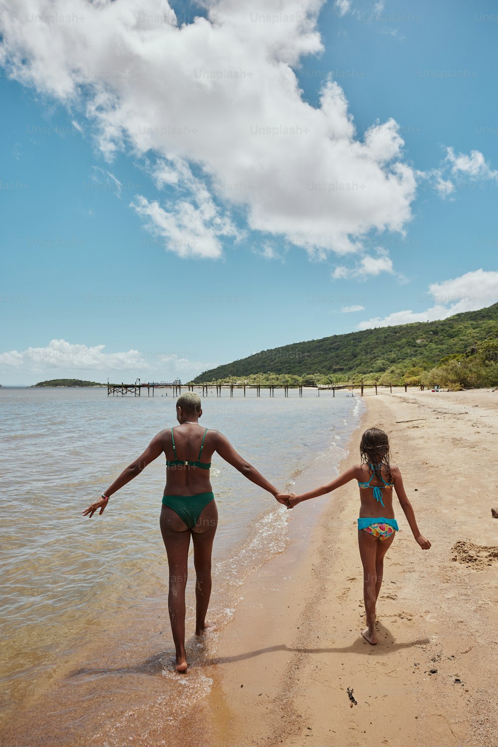 um homem e uma mulher que caminham em uma praia de mãos dadas