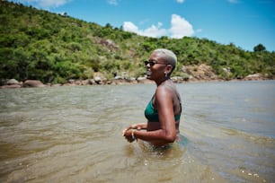 Una mujer en bikini verde vadeando en el agua