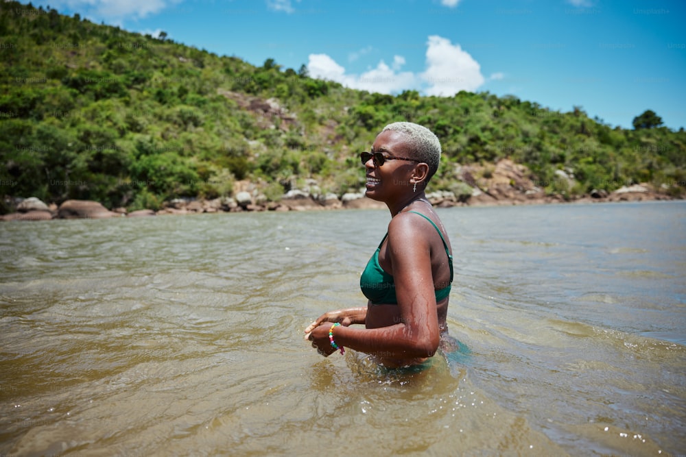 a woman in a green bikini wading in the water