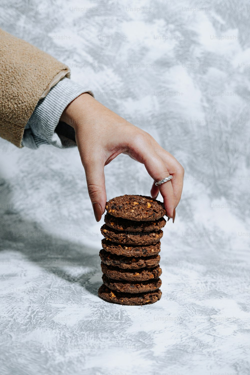 a hand reaching for a stack of cookies