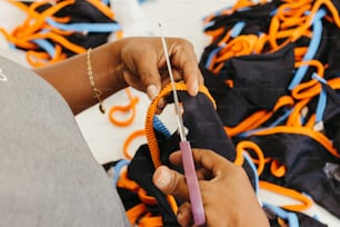 a person holding a pair of scissors in front of a pile of orange and blue