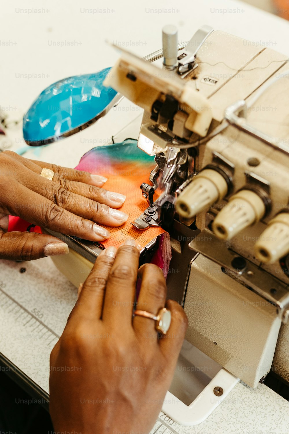 Una mujer está usando una máquina de coser para coser un trozo de tela