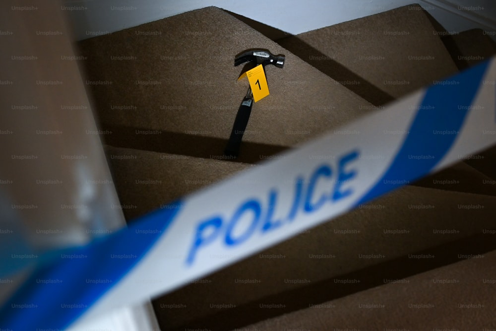 a hammer stuck in a cardboard box with a police tape around it