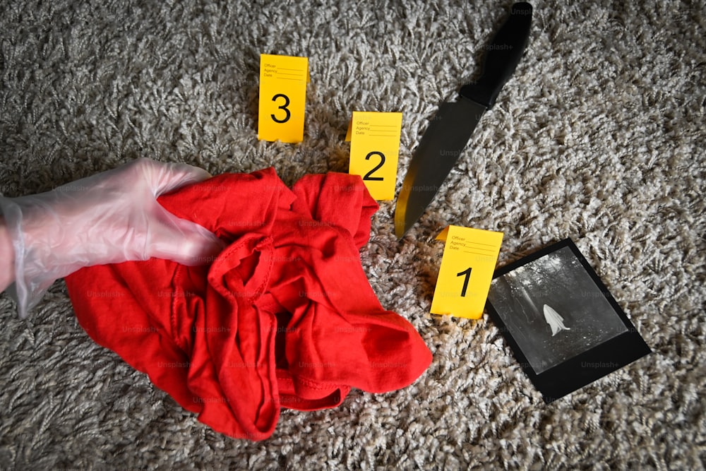 a pair of scissors, a knife, and a red shirt on the floor