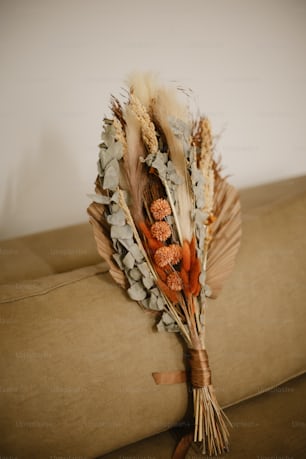 a bouquet of dried flowers sitting on top of a couch
