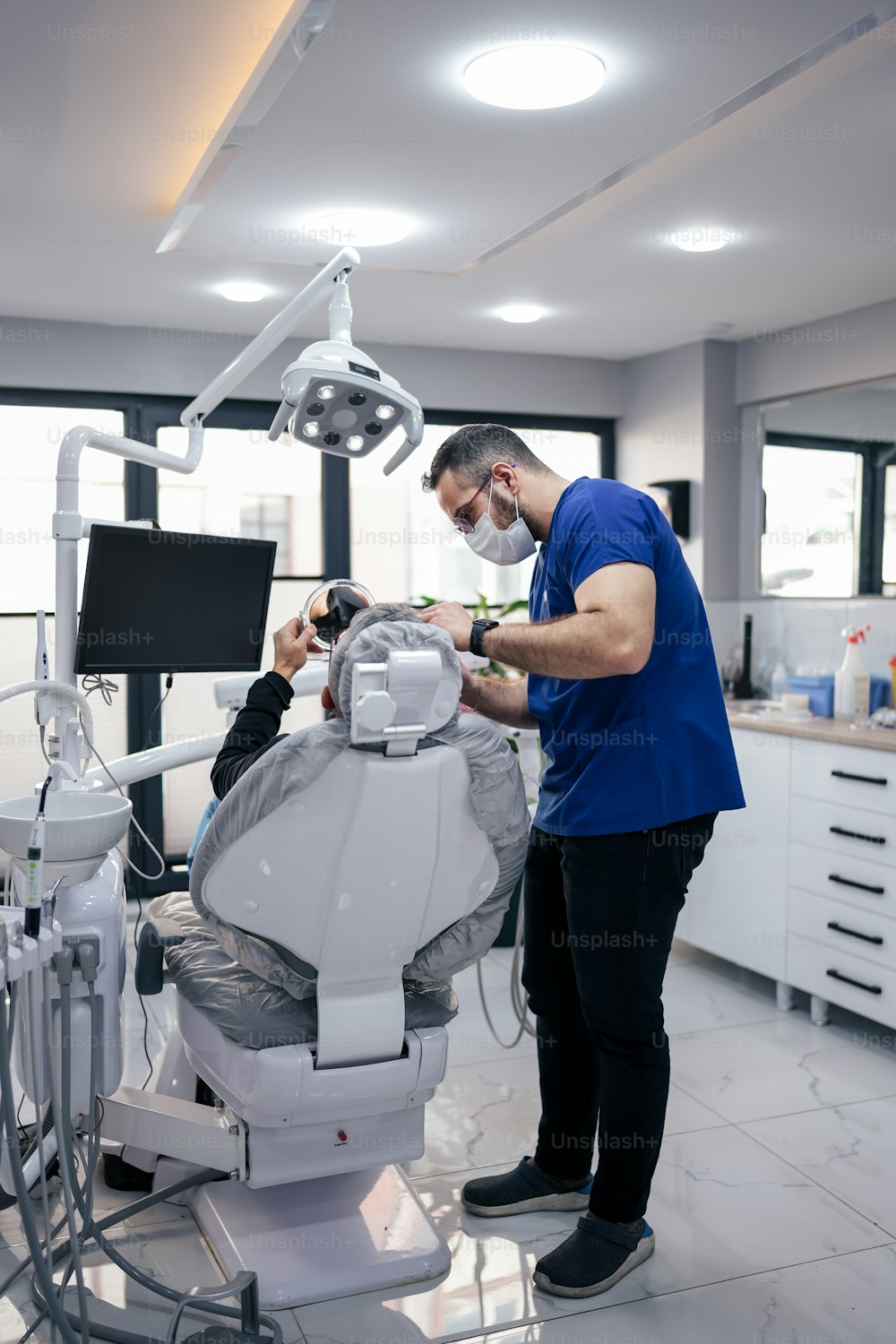 a man in a blue shirt standing next to a dentist chair