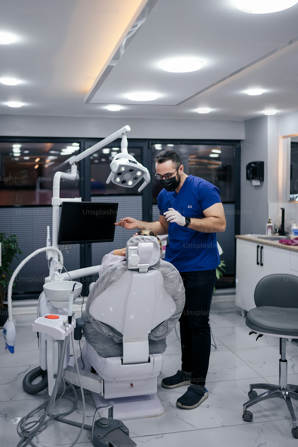 Un homme en chemise bleue debout à côté d’un fauteuil de dentiste