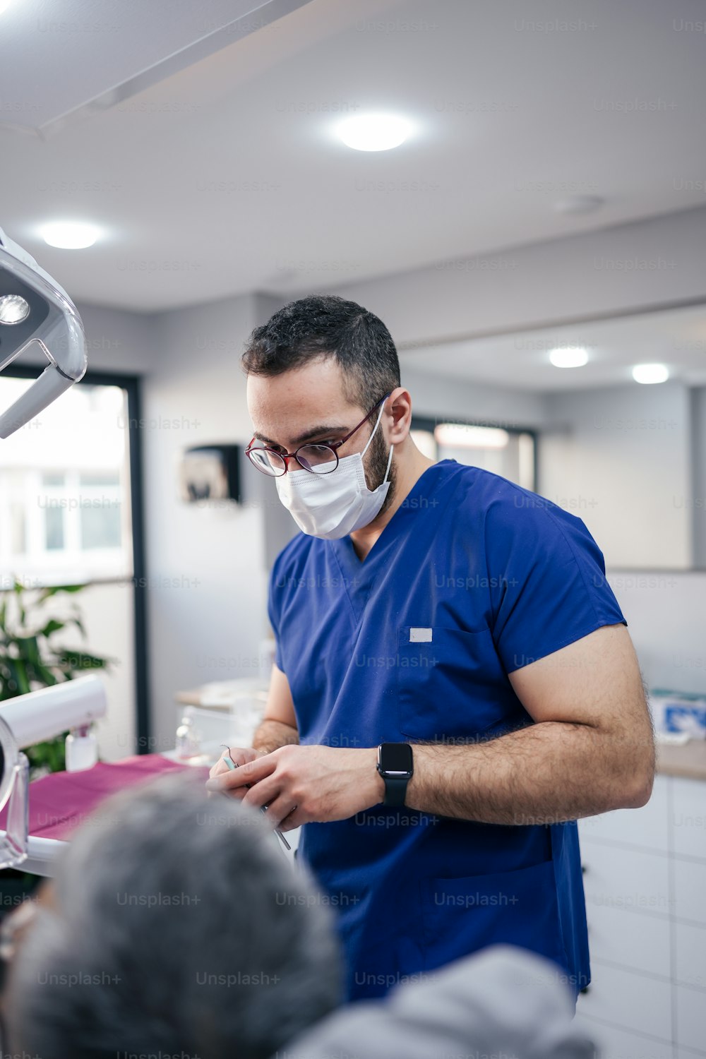 a man wearing a surgical mask standing in a dentist's office