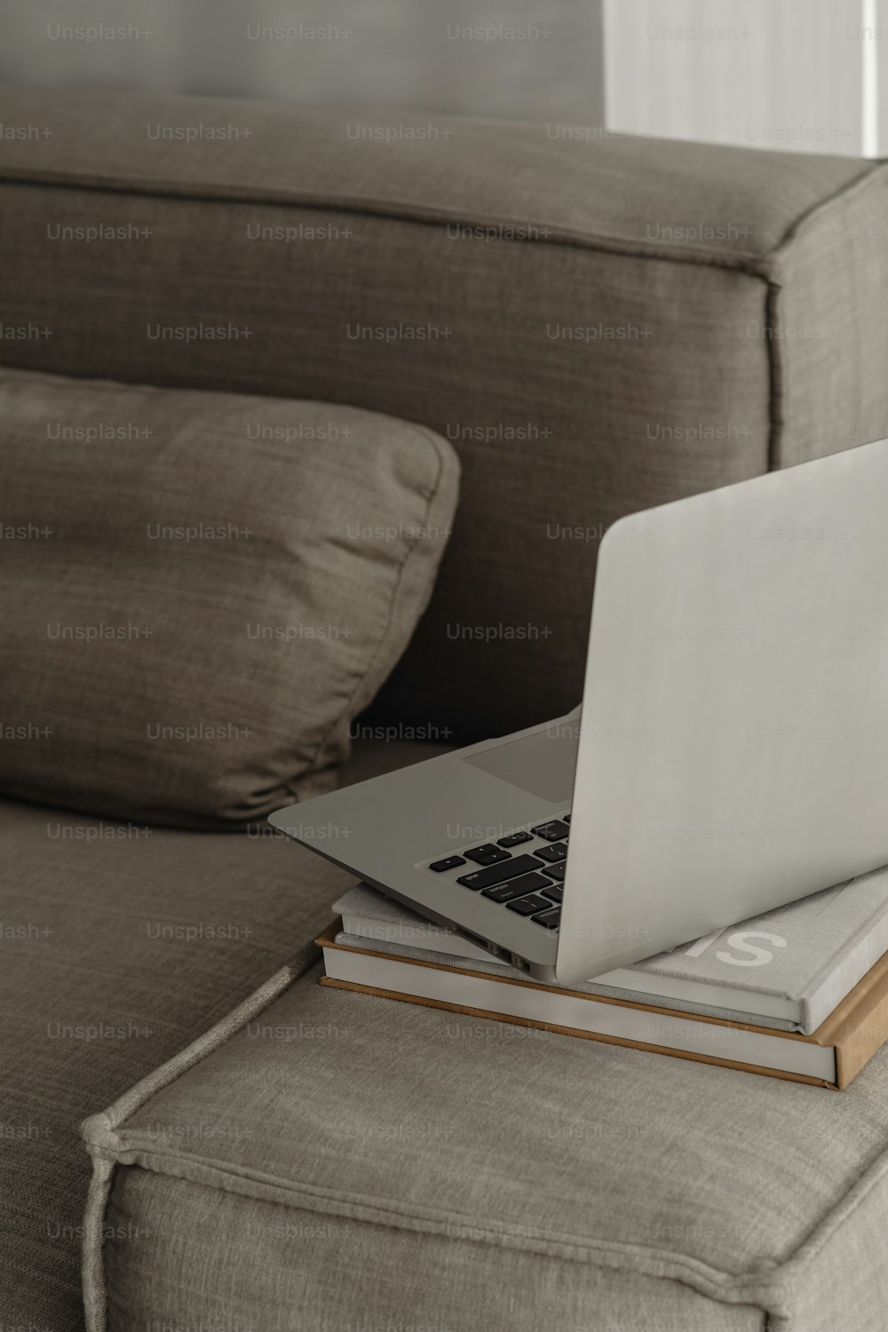 Ein Laptop sitzt auf einem Buch auf einer Couch