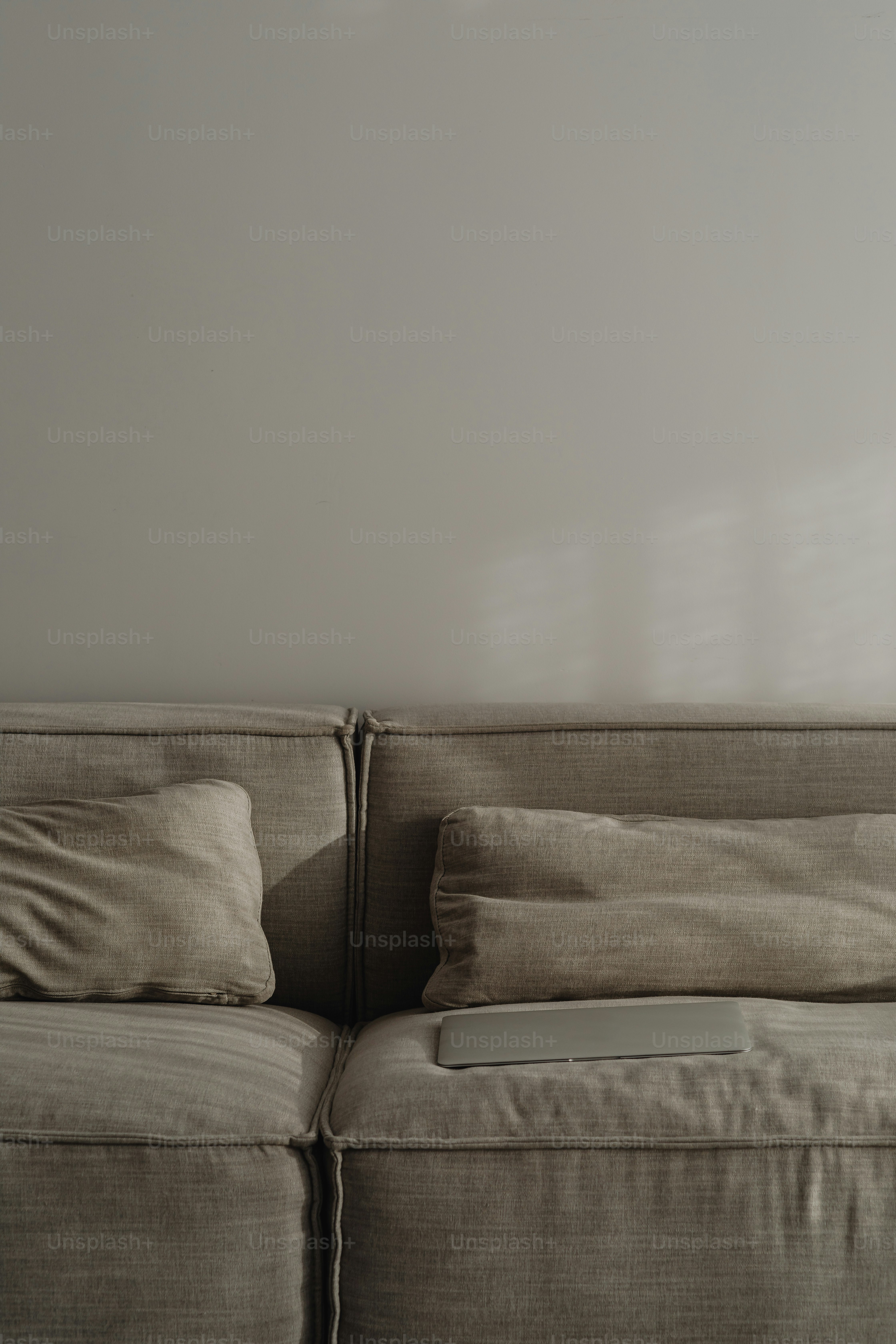 sofa dengan bantal dan remote control di atasnya