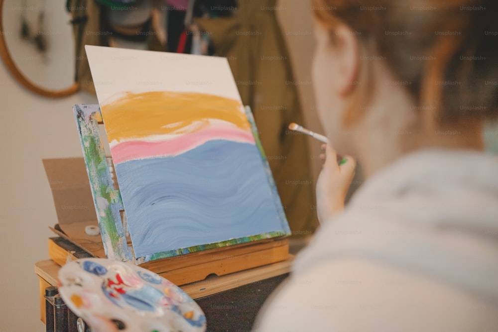 Una mujer está pintando un cuadro con un pincel