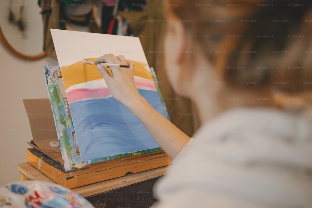 a woman is painting a picture on an easel