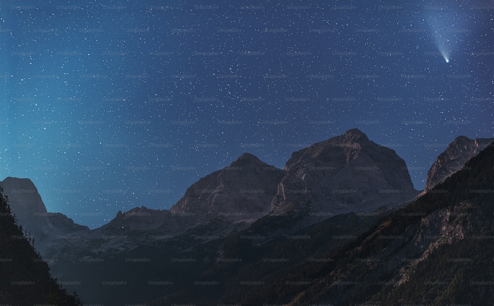 una vista di una catena montuosa di notte con una stella luminosa nel cielo