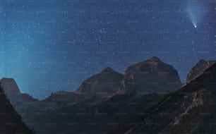 una vista di una catena montuosa di notte con una stella luminosa nel cielo