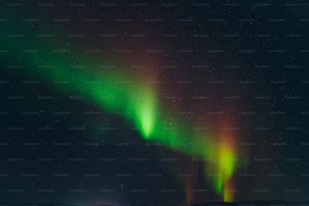 a green and red aurora bore in the night sky