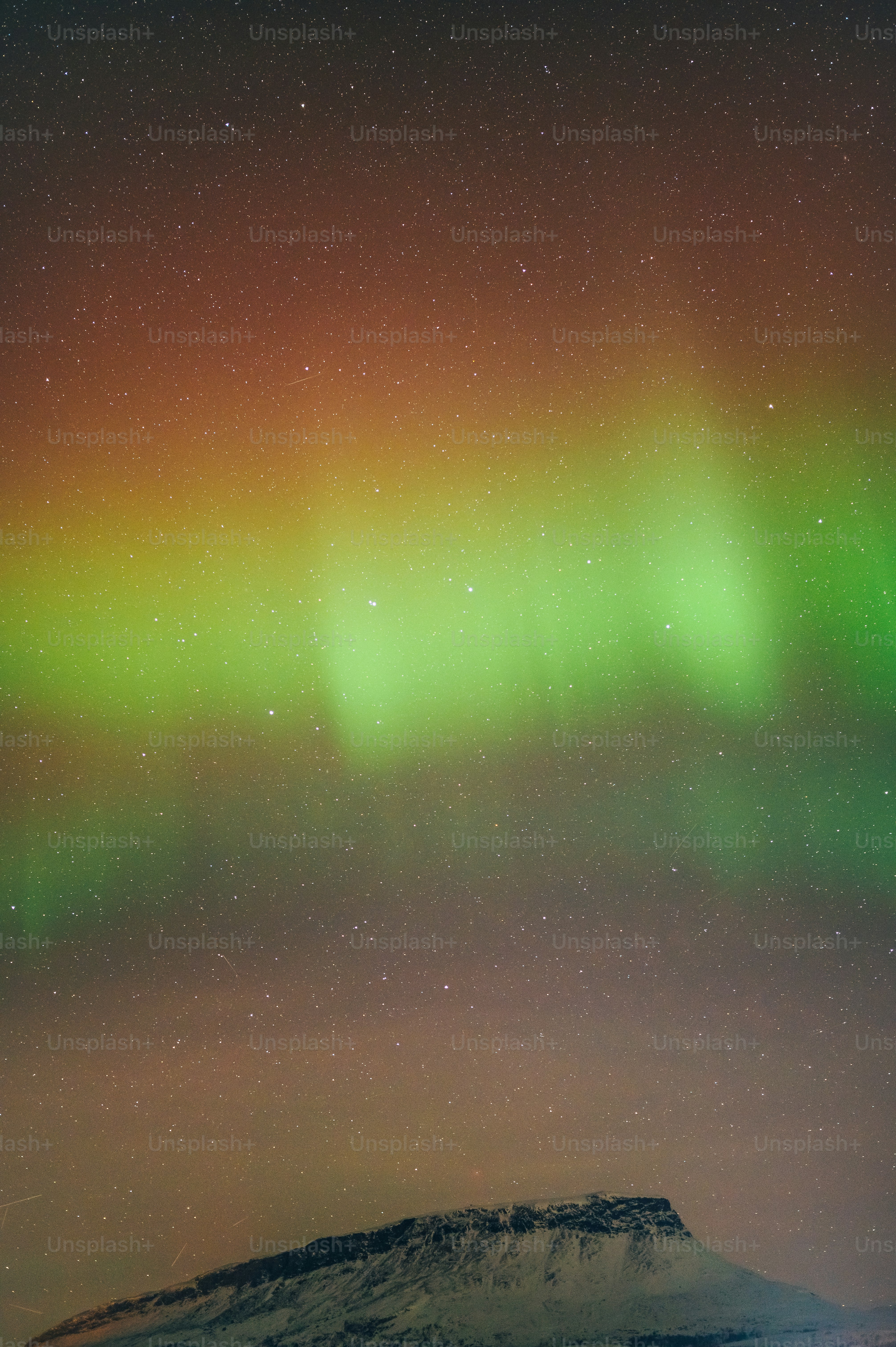a green and yellow aurora over a mountain