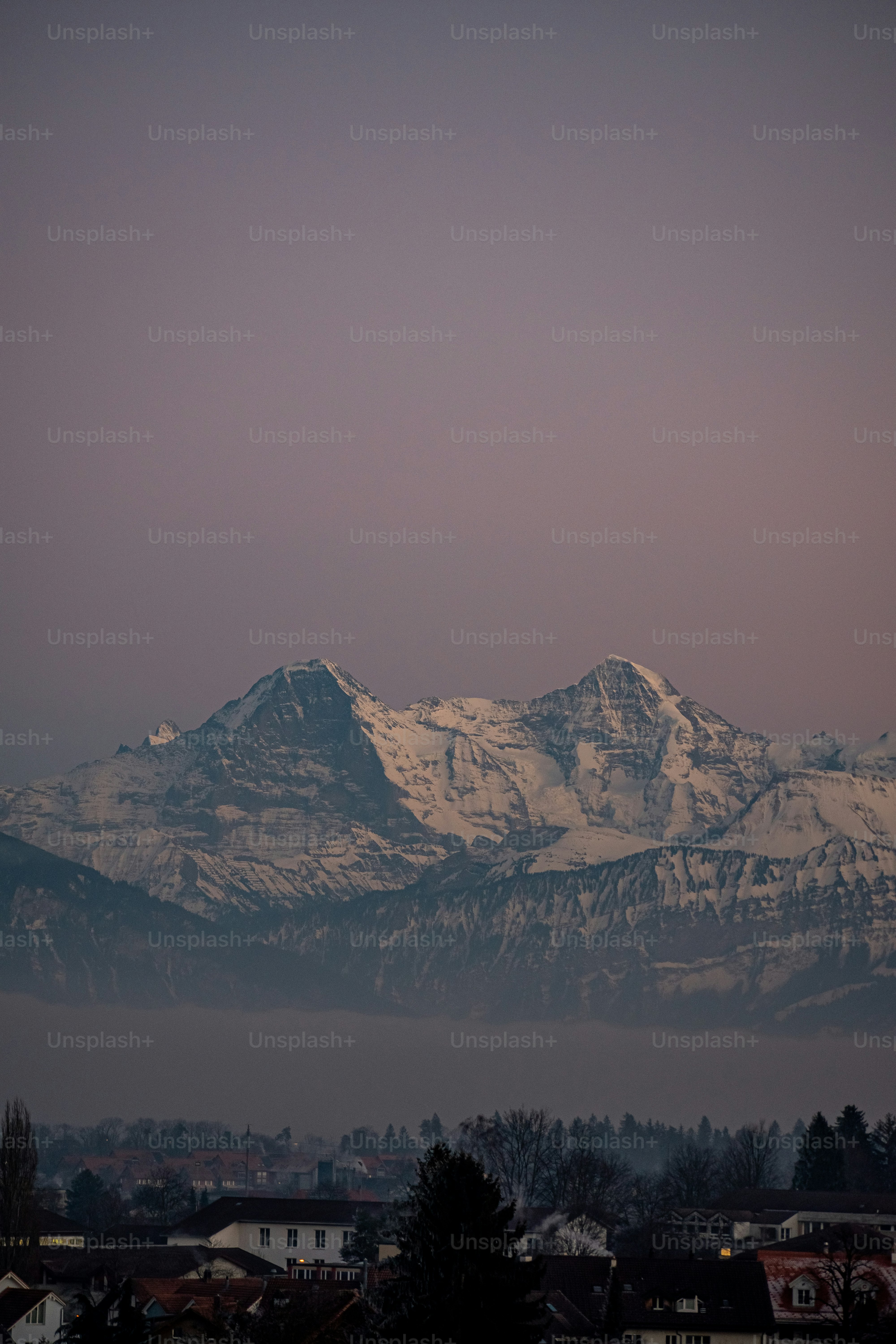 a snow covered mountain range with houses in the foreground
