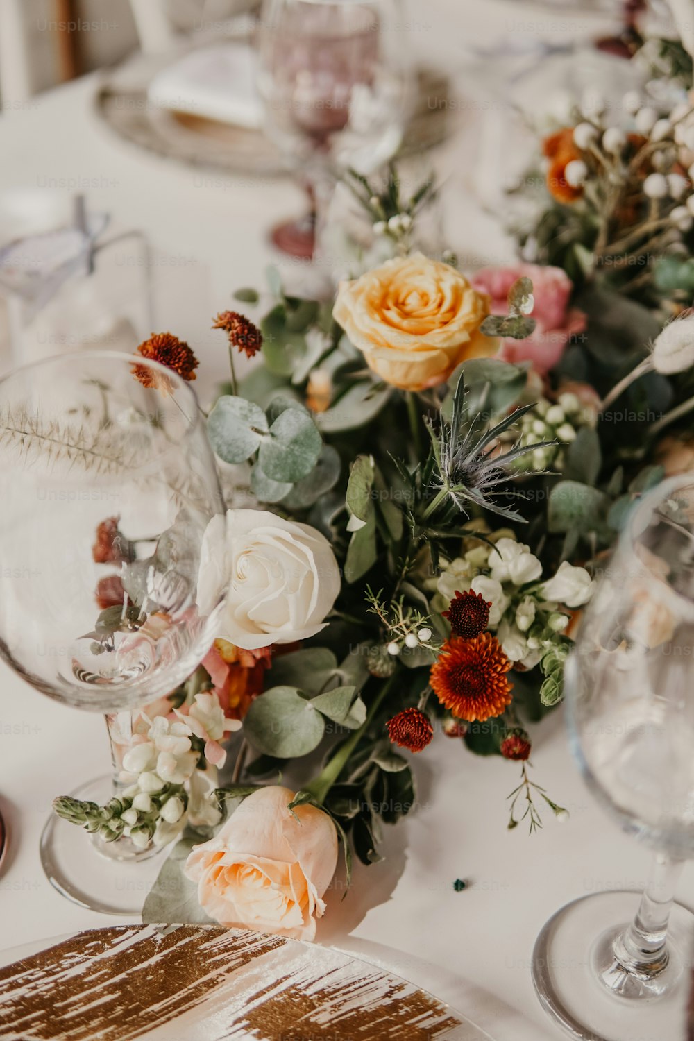 a close up of a table with flowers and wine glasses