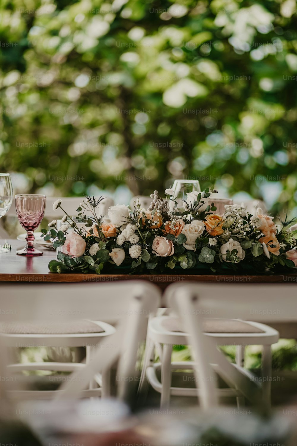 une table avec des fleurs et des verres à vin dessus