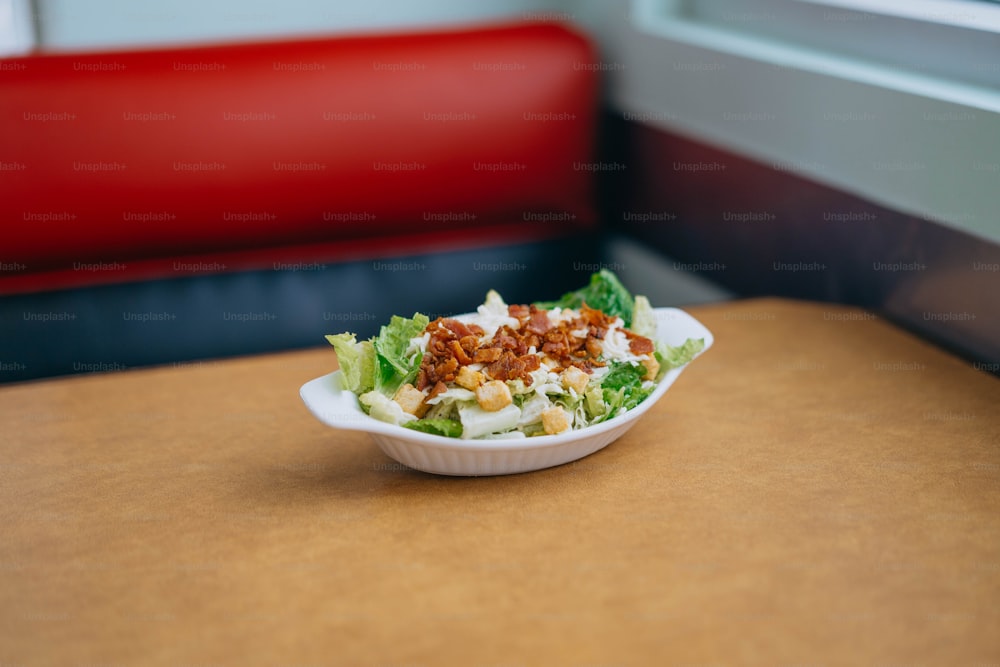 uma tigela branca recheada com salada em cima de uma mesa