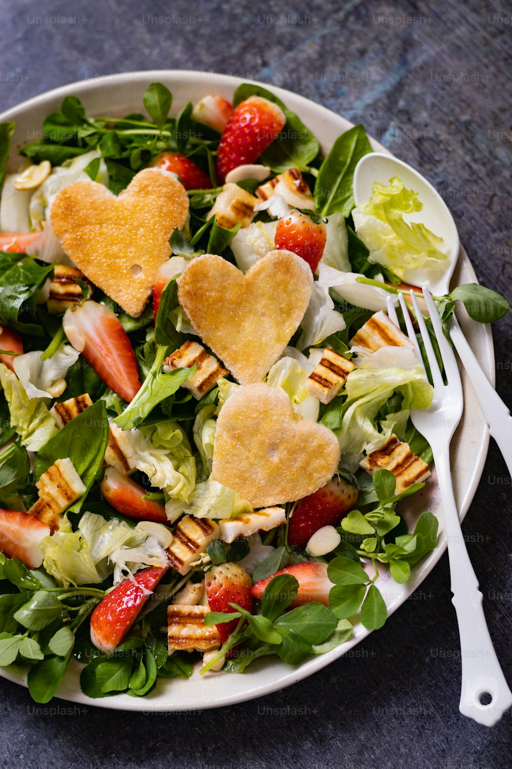 uma salada em forma de coração em um prato com um garfo